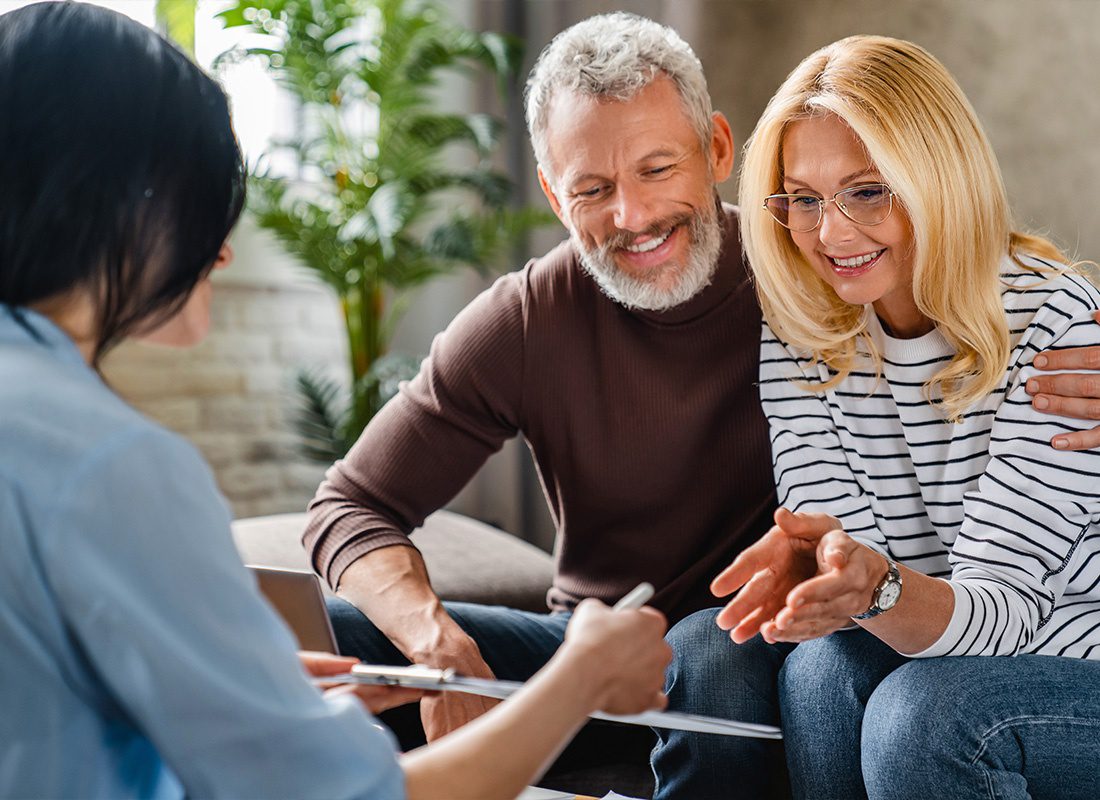 About Our Agency - An Estate Agent or Financial Adviser Showing a Terms of Contract to a Happy Couple on a Notepad